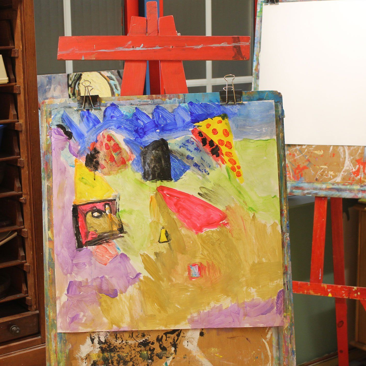 Een kleurrijk schilderij op een houten ezel naast een wit bord