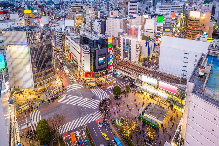 Vista aérea del cruce de Shibuya en Tokio, Japón, con peatones cruzando en una intersección concurrida rodeada de edificios altos y tiendas.