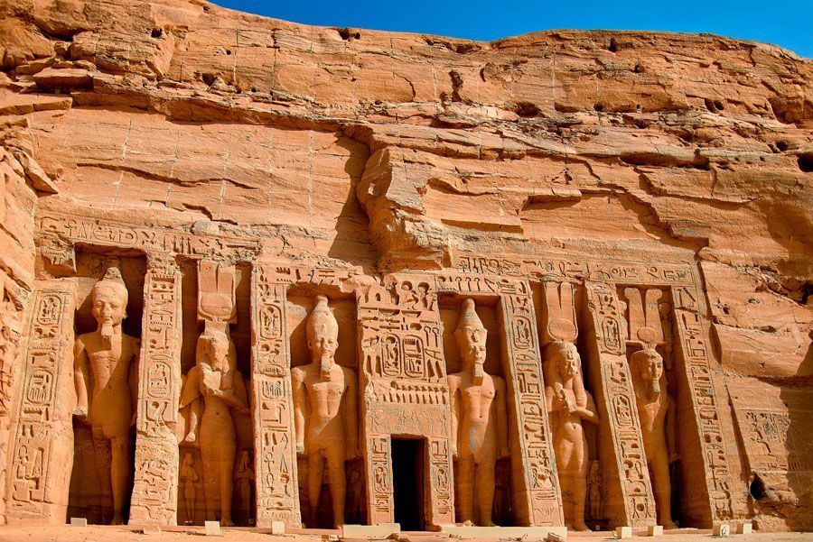 Exterior del templo de Abu Simbel en Egipto, con estatuas sentadas y tallas jeroglíficas en arenisca de color marrón rojizo.