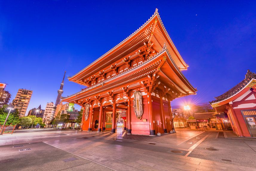 Puerta roja del Templo Senso-ji en Tokio, Japón, al anochecer. Iluminada contra un cielo azul oscuro, con la Tokyo Skytree visible al fondo.