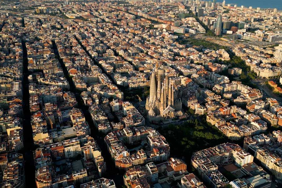 Vista aérea de Barcelona, España, con un trazado de calles en cuadrícula. Destaca la Sagrada Familia, rodeada de una densa urbanización.