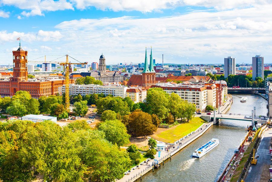 Vista aérea de Berlín, Alemania, que muestra un río, edificios, árboles y un cielo azul con nubes.