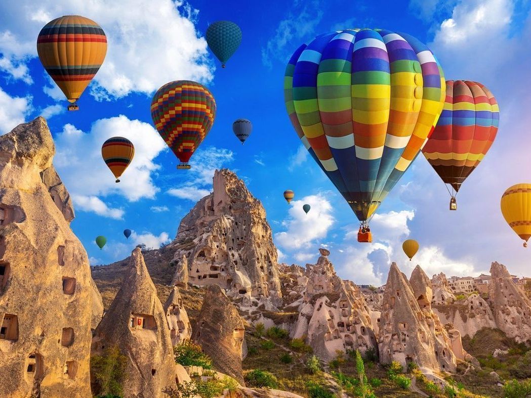 Globos aerostáticos sobre formaciones rocosas en Capadocia, Turquía. Colores vibrantes contra un cielo azul brillante.