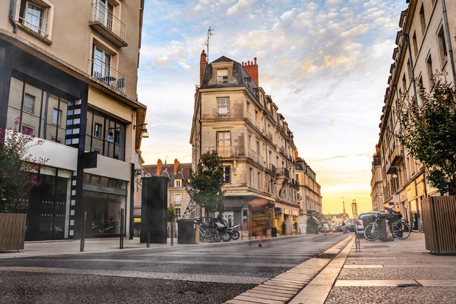 Escena callejera en una ciudad europea al atardecer. Los edificios bordean la calle, ligeramente húmeda.