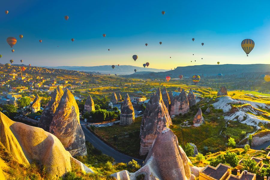 Los globos aerostáticos flotan sobre las formaciones rocosas únicas de Capadocia, Turquía, al amanecer, proyectando una luz cálida.