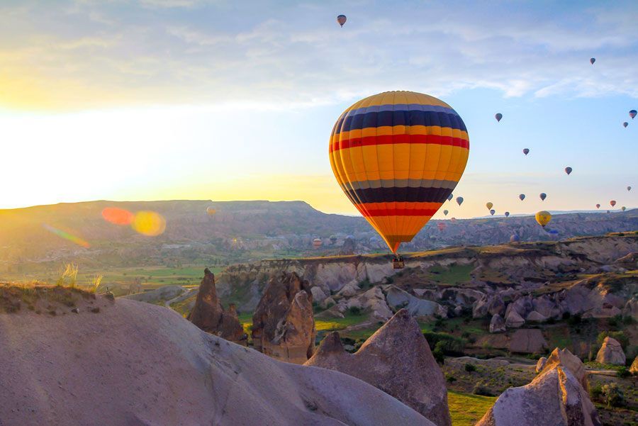Globo aerostático sobrevolando Capadocia, Turquía, al amanecer. Otros globos salpican el cielo y las distintivas formaciones rocosas.