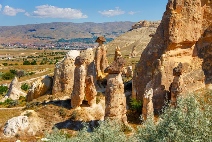 Formaciones rocosas erosionadas en Capadocia, Turquía, con cimas en forma de hongo bajo un cielo azul brillante.