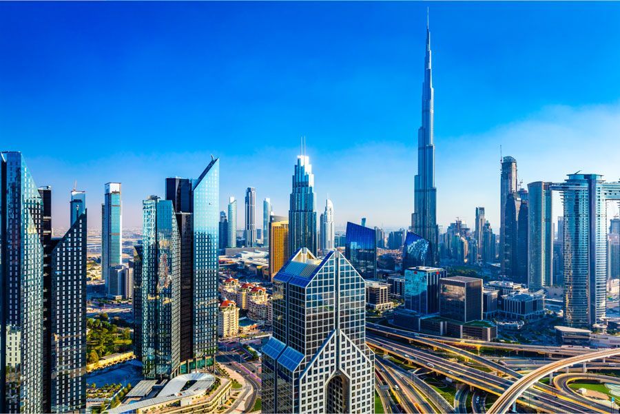 El horizonte de Dubái con el Burj Khalifa elevándose sobre modernos rascacielos bajo un cielo azul claro.
