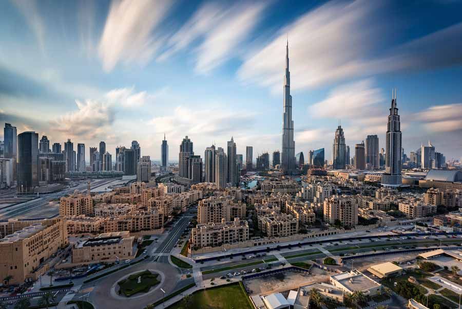 El horizonte de Dubai con el Burj Khalifa dominando, bajo un cielo azul nublado.