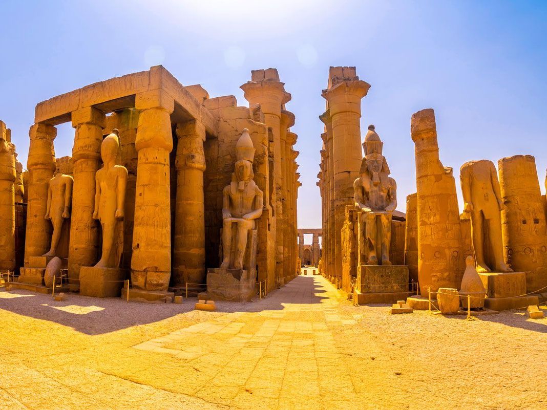 Ruinas antiguas del Templo de Luxor en Egipto, con estatuas y columnas bañadas por la cálida luz del sol.