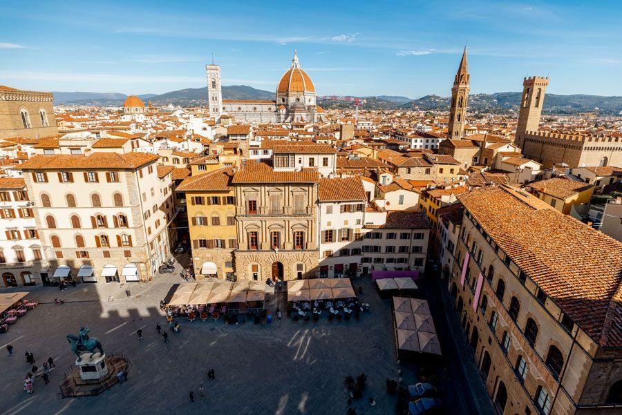 Una vista panorámica soleada de Florencia, Italia, con edificios, una plaza y la catedral del Duomo dominando el horizonte.