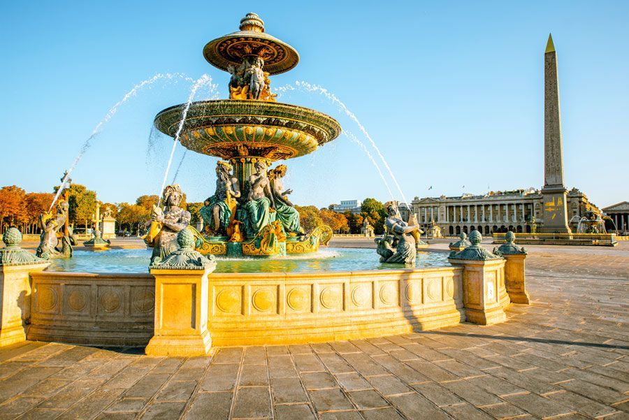 Fuente en la Plaza de la Concordia, París, con chorros de agua. Al fondo, el Obelisco de Luxor y otros edificios.