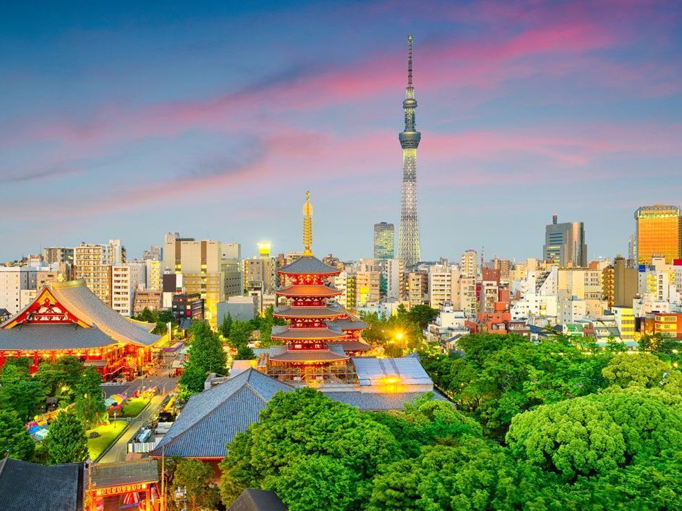 Horizonte de Tokio con una pagoda, un templo, la Torre Tokyo Skytree y edificios de la ciudad bajo un cielo colorido al atardecer.