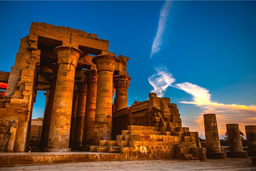 Ruinas de un antiguo templo en Egipto, con altas columnas bajo un cielo azul vibrante. La estructura de piedra brilla bajo la cálida luz del sol.