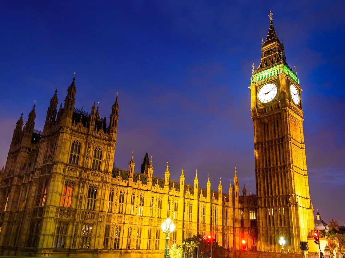 La torre del reloj iluminada, el Big Ben, se encuentra junto a las Casas del Parlamento en Londres al anochecer.