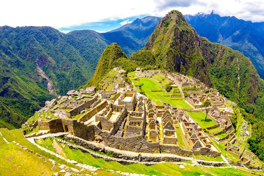 Machu Picchu, Perú, una antigua ciudadela inca, ubicada entre exuberantes montañas verdes bajo un cielo azul.