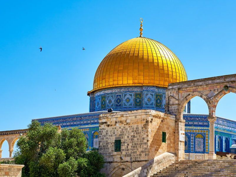 Mezquita de la Cúpula de la Roca en Jerusalén, Israel. Cúpula dorada y paredes de azulejos azules bajo un cielo azul brillante.