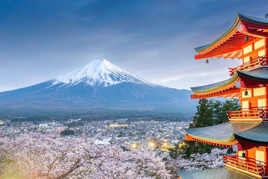 Monte Fuji con su pico nevado, pagoda roja, flores de cerezo y una ciudad en la base.