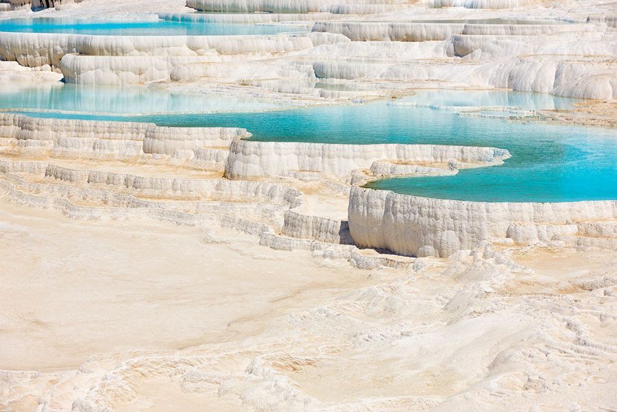 Terrazas de travertino con piscinas de agua turquesa que caen en cascada, formando un paisaje natural en Pamukkale, Turquía.