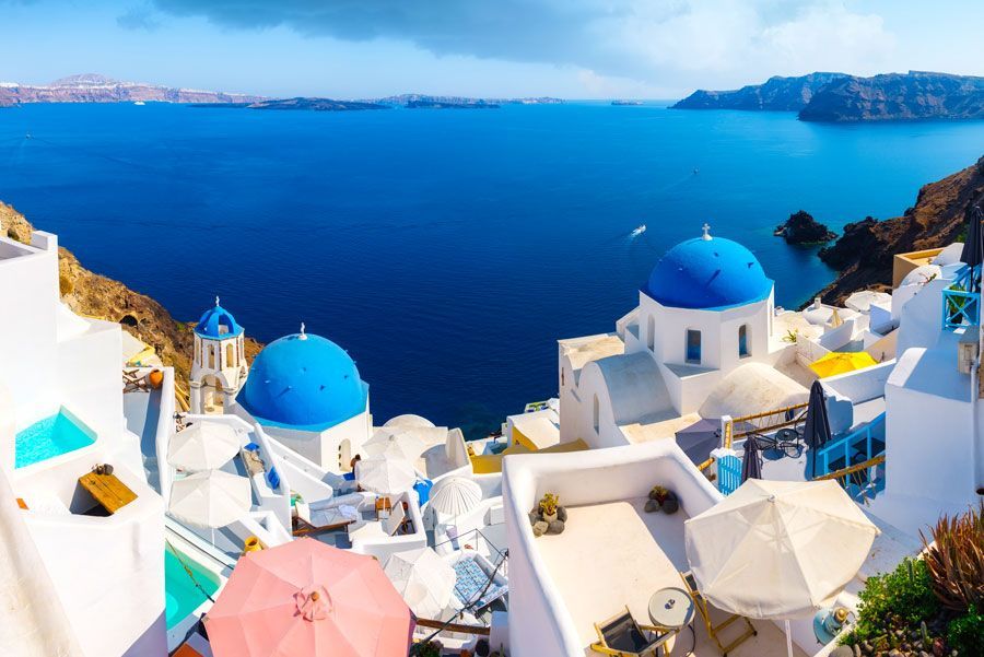 Edificios blancos con cúpulas azules y vistas al mar Egeo en Santorini, Grecia.
