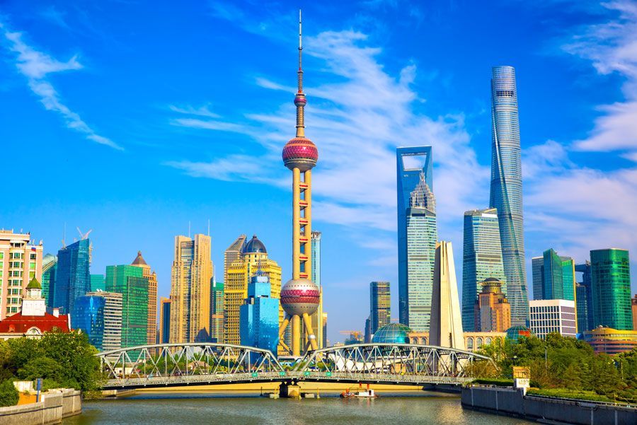 El horizonte de Shanghai con la Torre Perla Oriental, rascacielos y un puente sobre un río en un día soleado.
