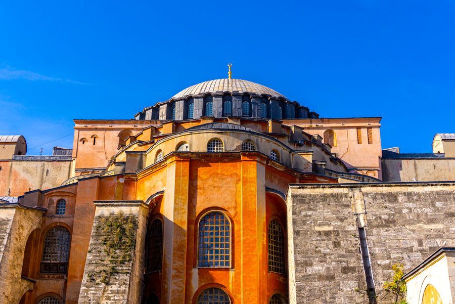 Santa Sofía en Estambul, Turquía, vista exterior bajo un cielo azul brillante. Edificio de ladrillo naranja y beige con una gran cúpula.