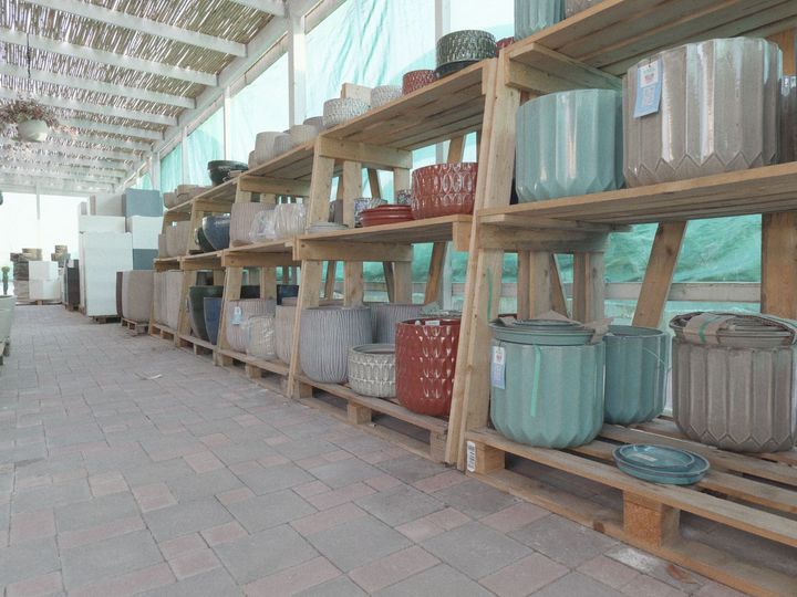 Scaffali di vasi e contenitori in ceramica in una corsia coperta di un mercato all'aperto.