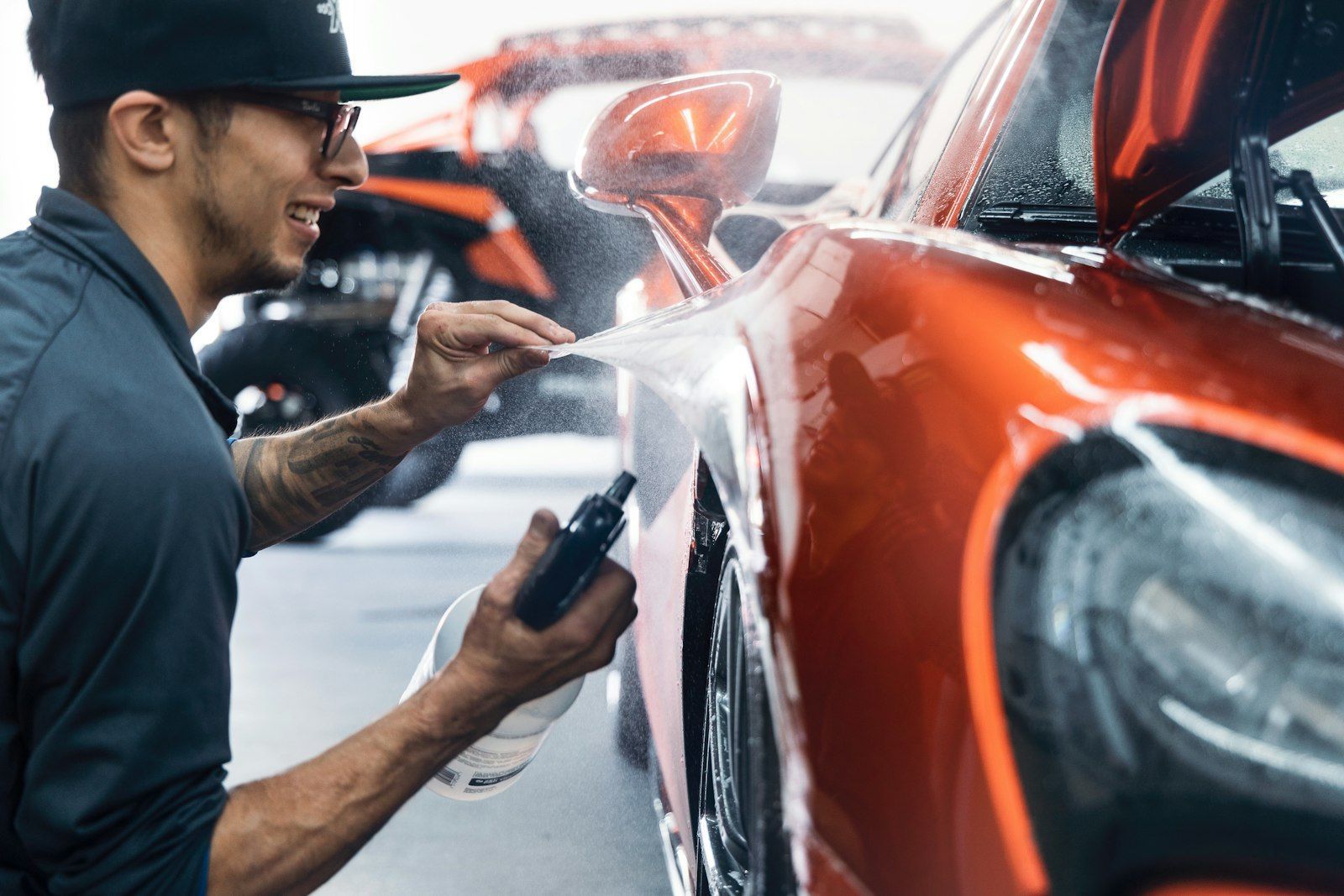 Technician working on an orange car in a repair shop