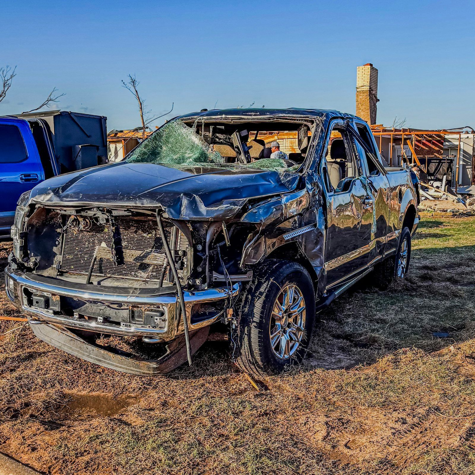 Heavily damaged pickup truck with a crushed front end and exposed frame.