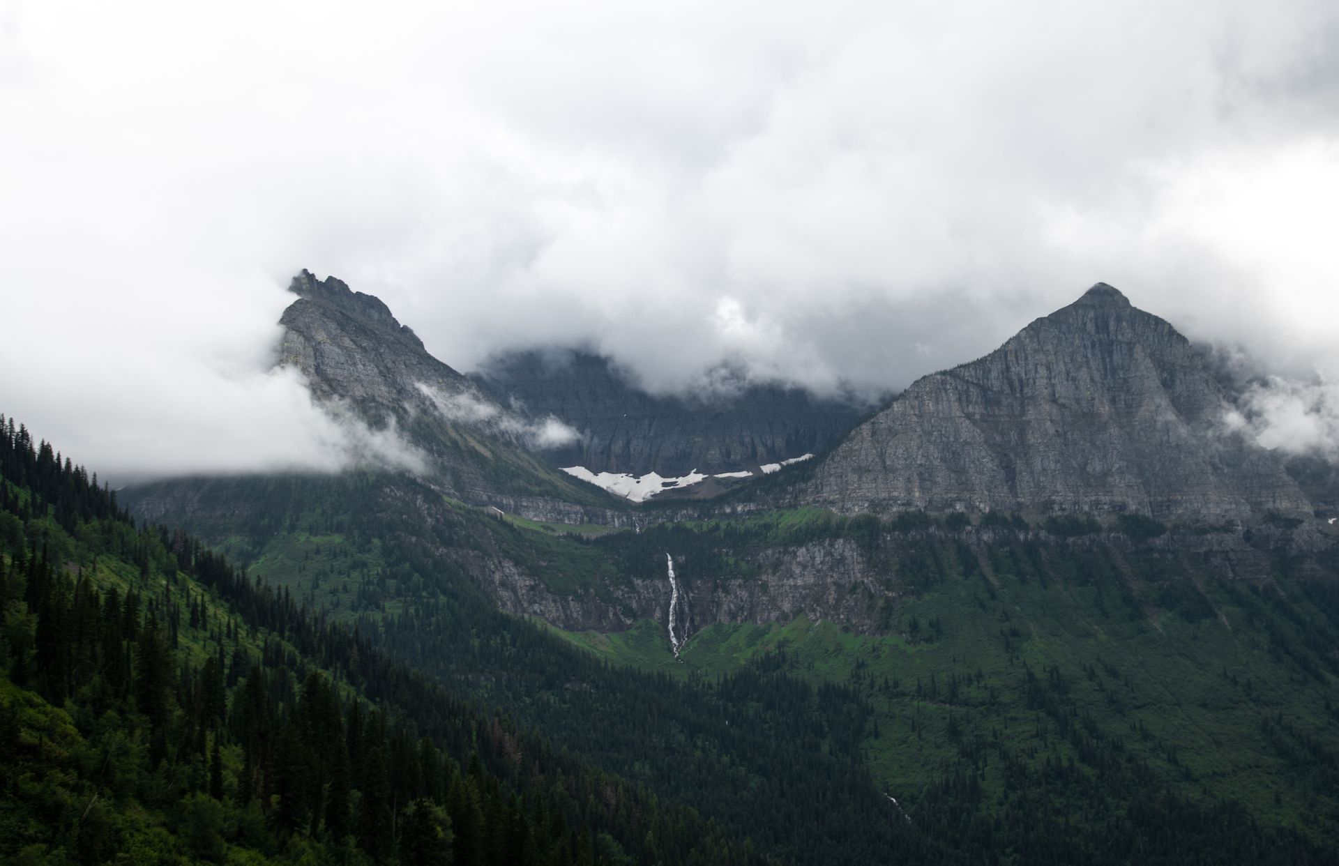 Bird Woman Falls cascading down Mt Oberlin shrouded in storm clouds at Glacier National Park