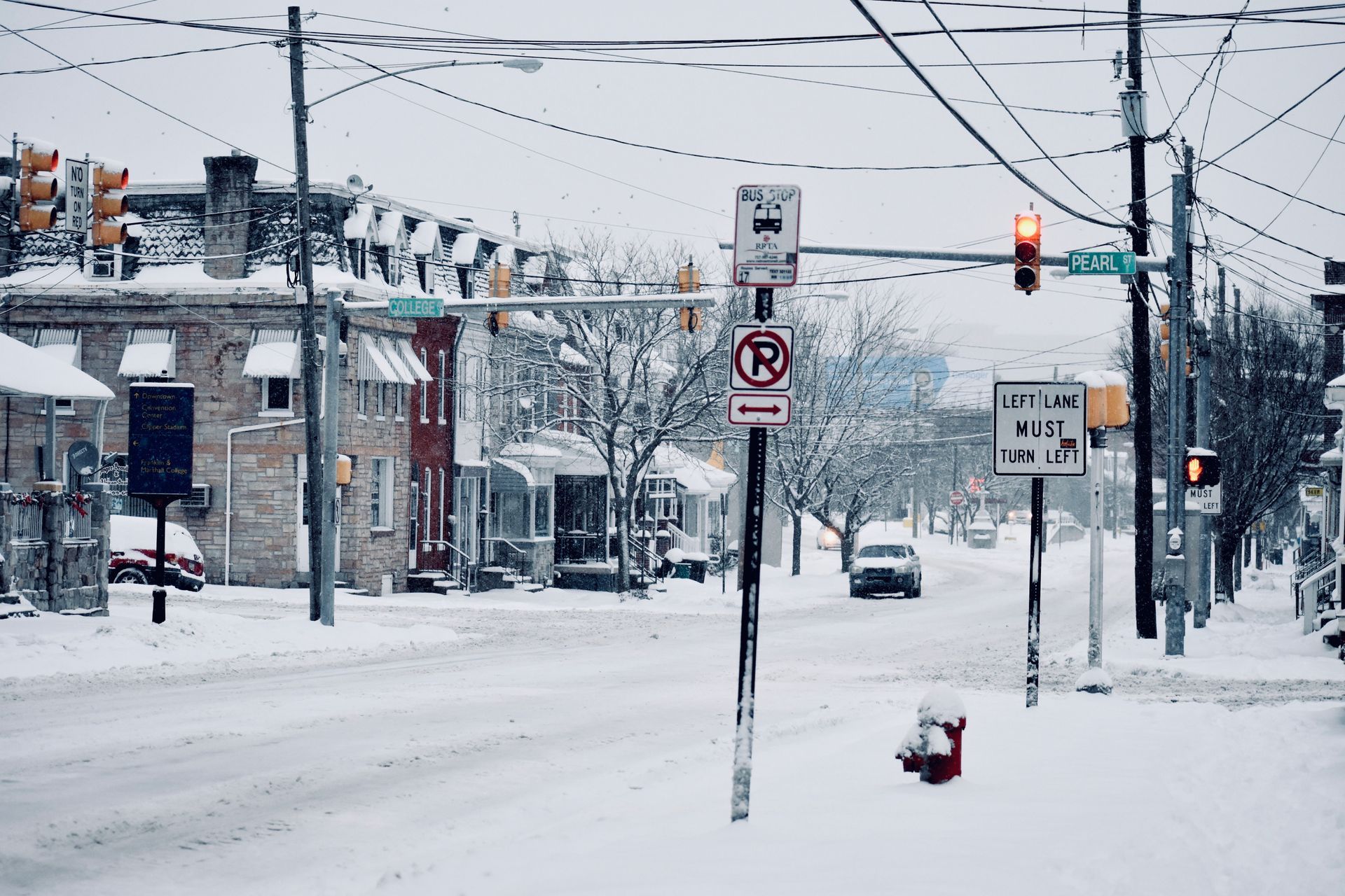 A snowy intersection at College and Pearl Street with a local bus stop sign in Pottstown, Pennsylvania.
