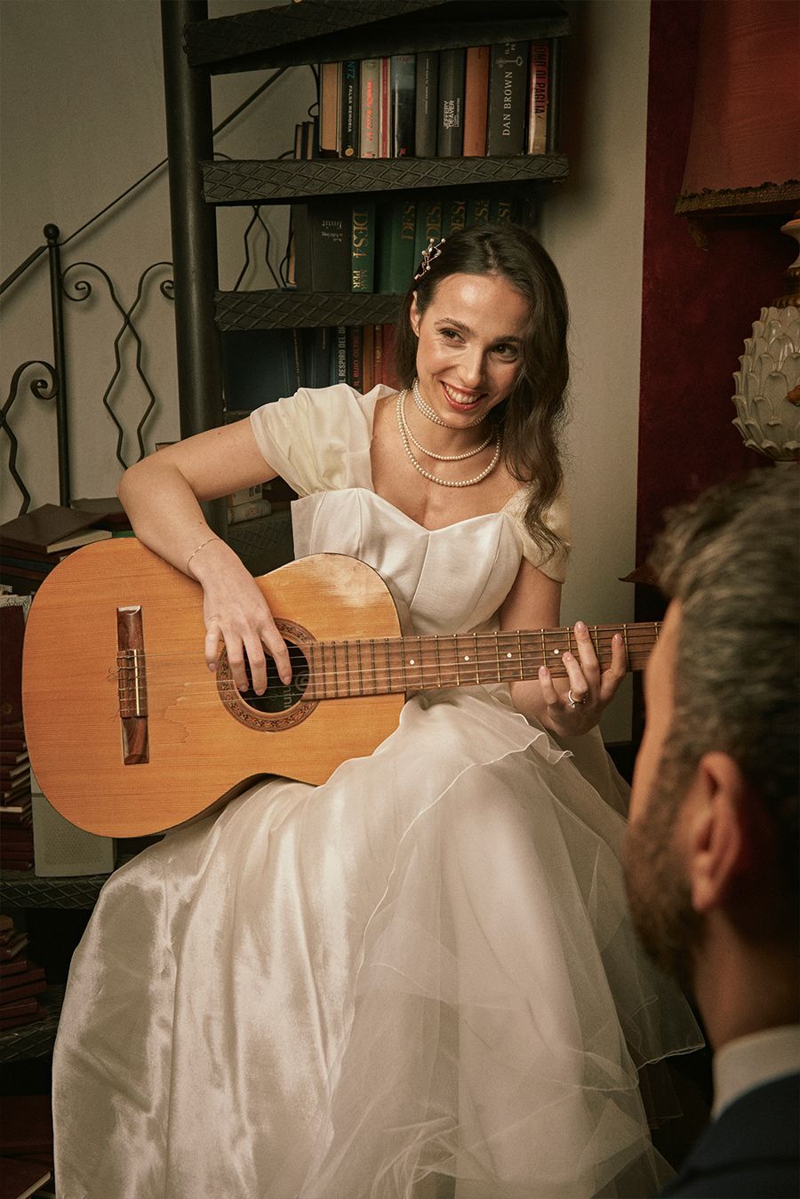 Una donna in abito da sposa suona la chitarra accanto a un uomo.