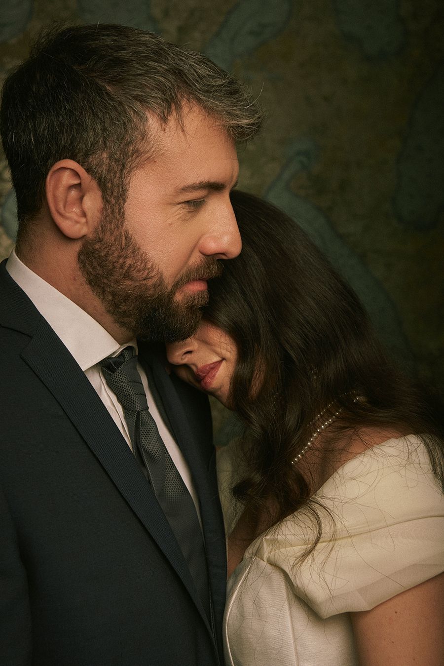 Un uomo in giacca e cravatta abbraccia una donna in abito da sposa.