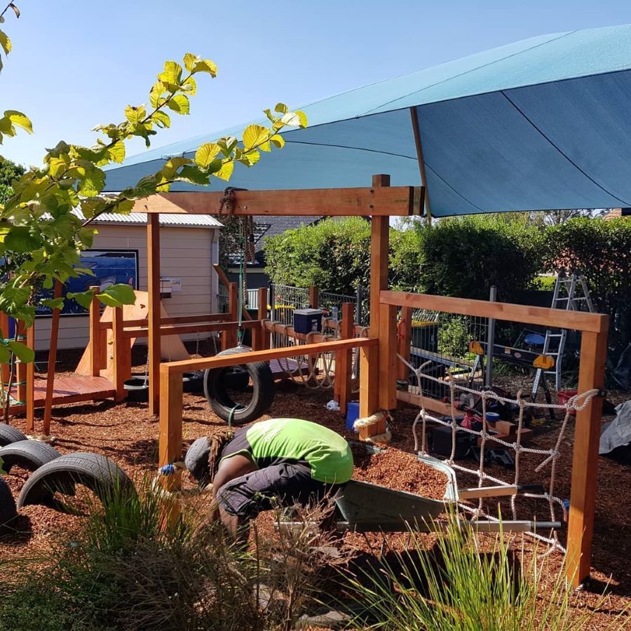 A Man is Working on a Playground Under a Blue Umbrella — Garden Vogue in Lake Macquarie, NSW