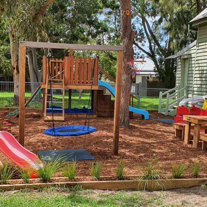 A Playground With a Slide and Swings in Front of a House — Garden Vogue in Charlestown, NSW