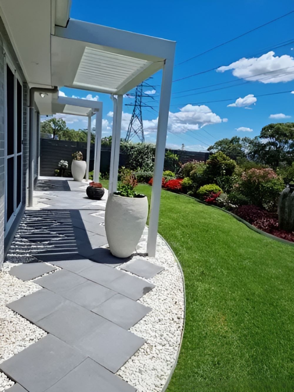 A Patio With a Pergola and Potted Plants in Front of a House — Garden Vogue in Charlestown, NSW