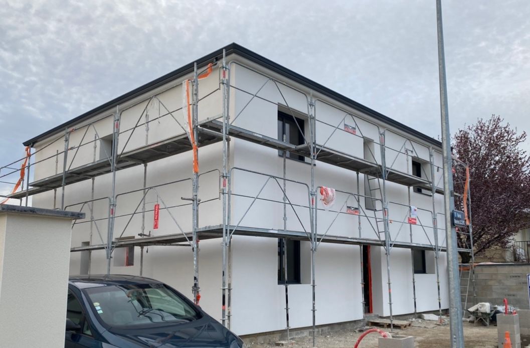 Une voiture est garée devant un immeuble en construction.