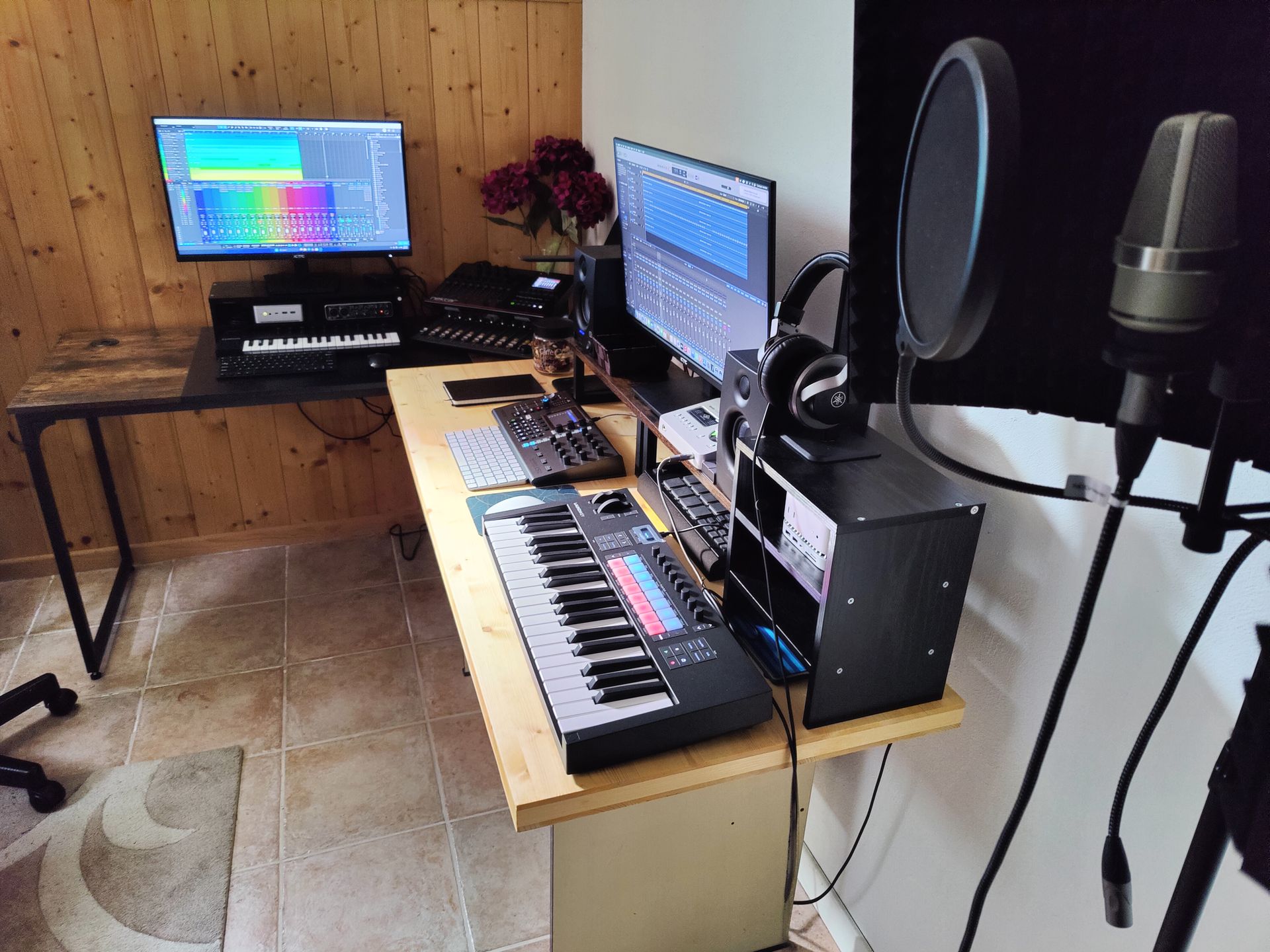 Music studio: two computer monitors, keyboard, microphone, and recording equipment.