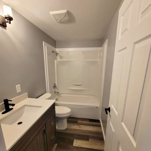 Bathroom renovation with a dark brown  vanity, new flooring, and tub.