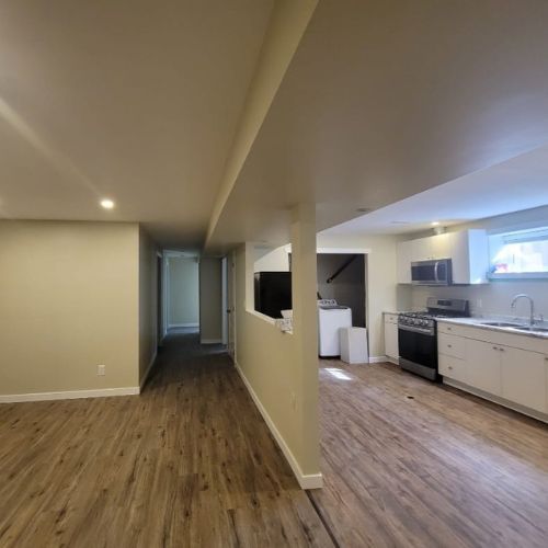 A newly renovated basement with new flooring, kitchen area, and living room.