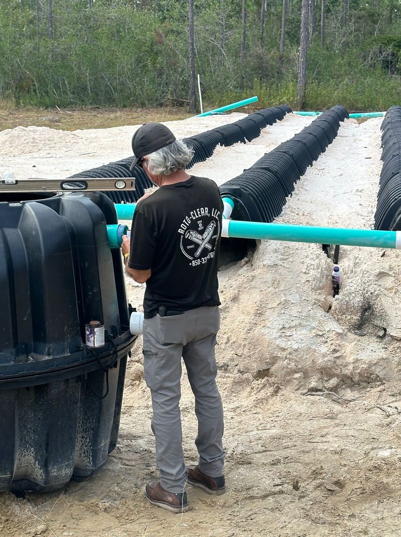 Man installing septic system with gravel beds and black tank.