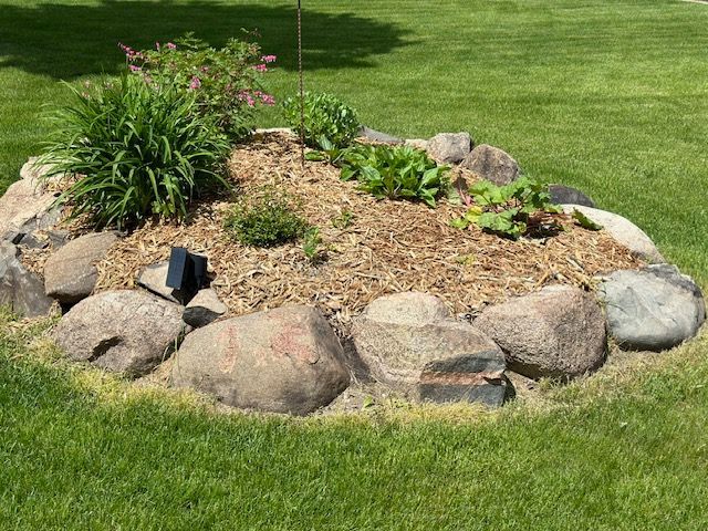 A rock garden in the middle of a lush green lawn.