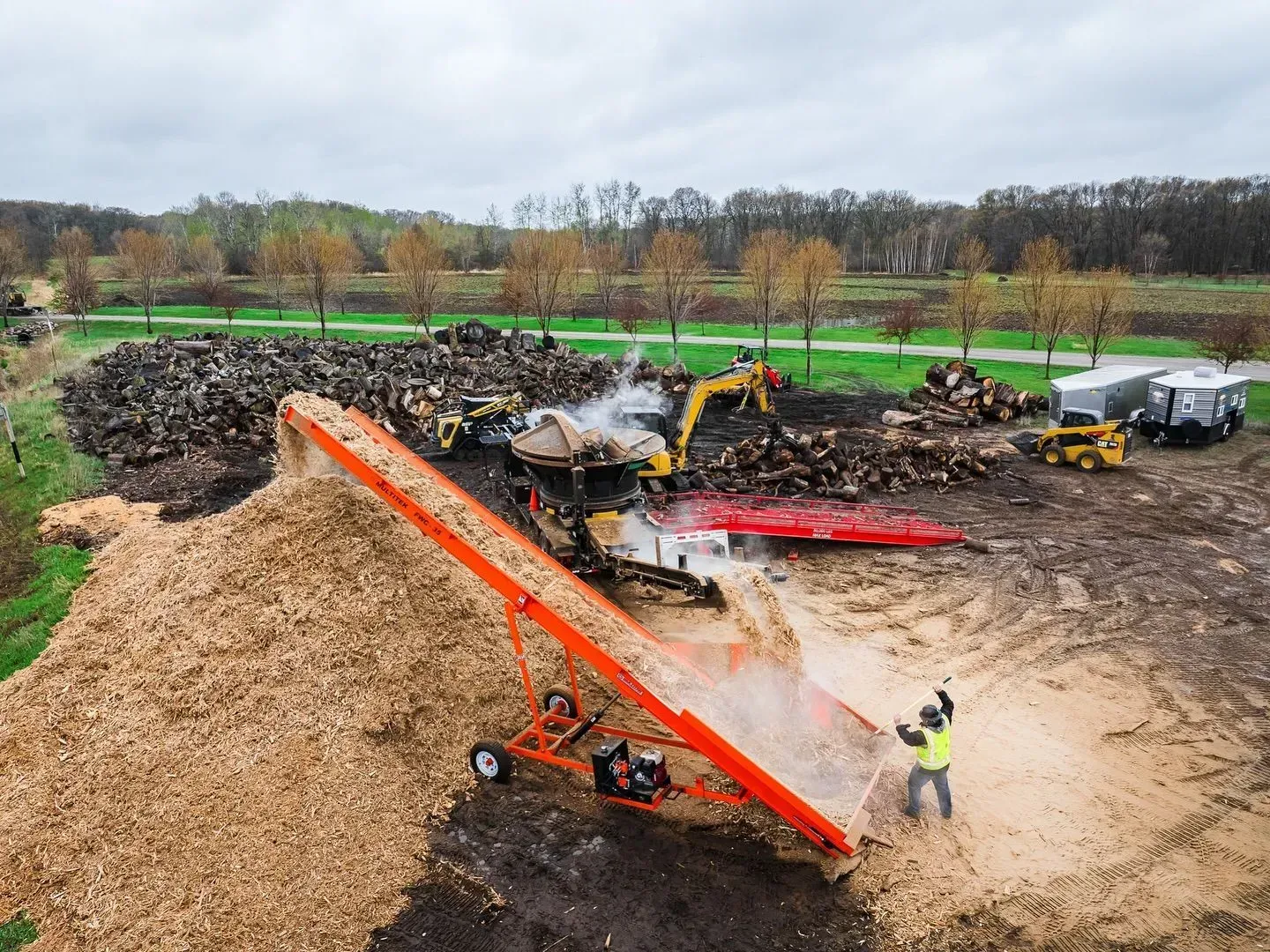 An aerial view of a pile of wood chips being loaded into a truck.