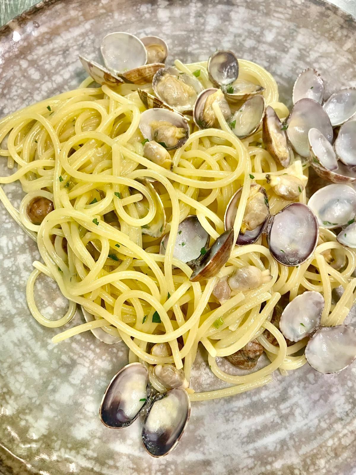 Spaghetti alle vongole in brodo leggero su un piatto di ceramica
