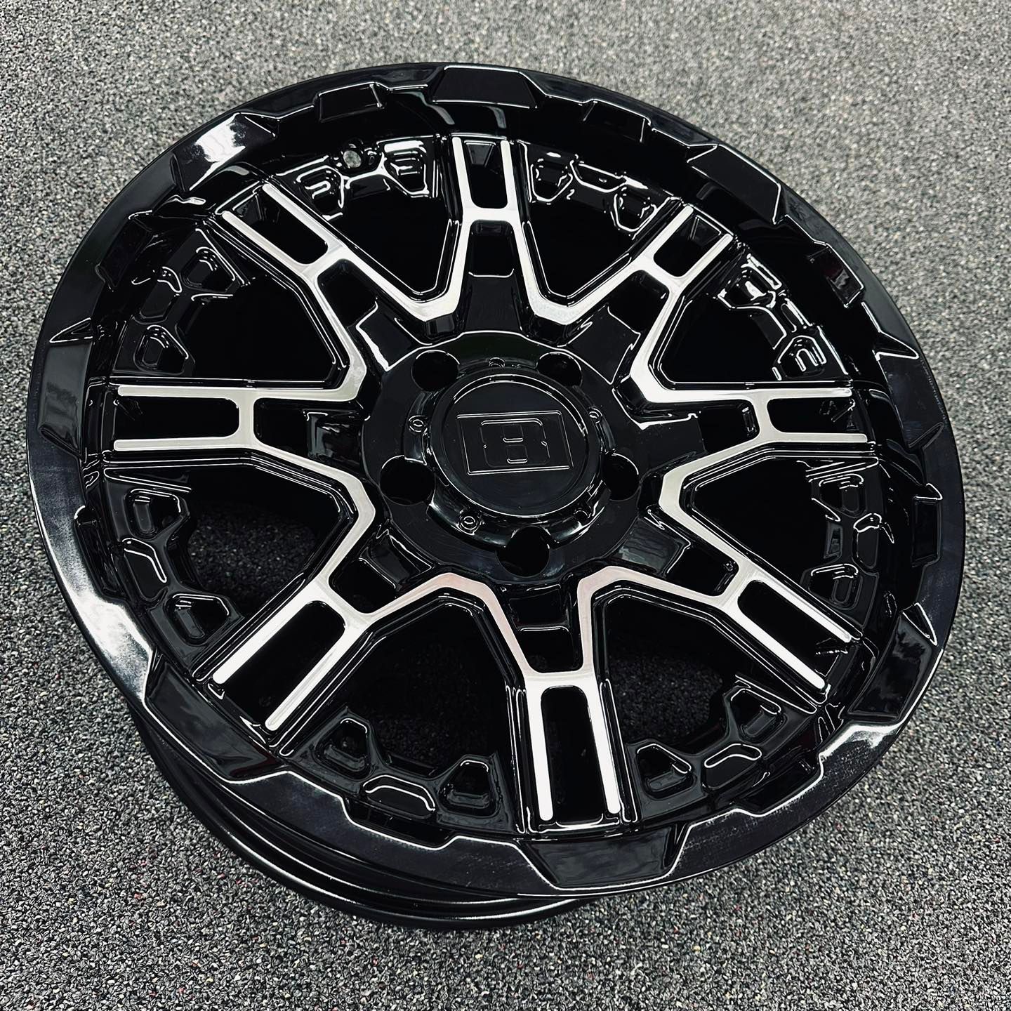 Black and silver multi-spoke wheel rim on a gray surface
