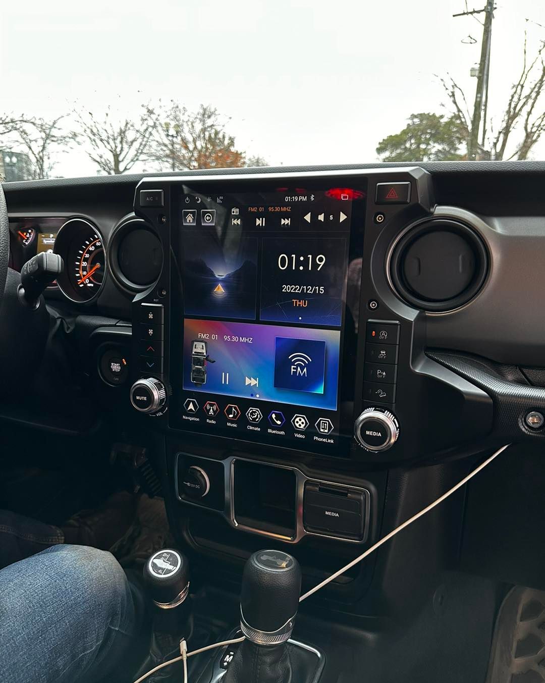 Car dashboard with a central touchscreen showing a music interface and gauges, viewed from the front seats