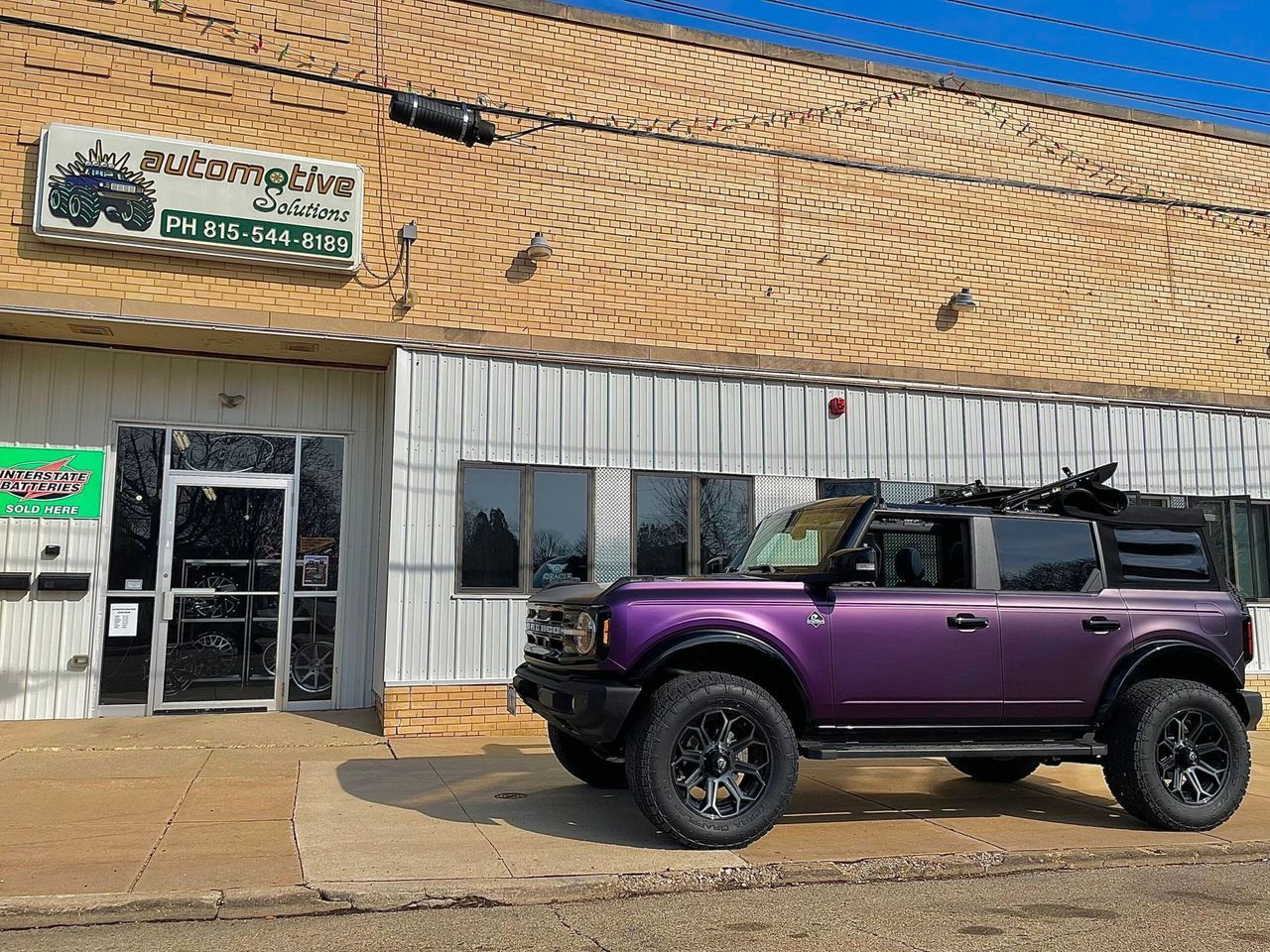 Purple SUV parked outside a storefront with Arabic signage on a sunny street