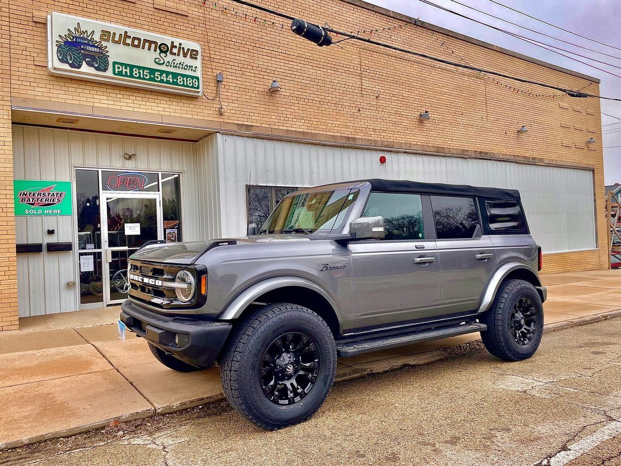 Gray lifted SUV parked outside a storefront with Thai signage