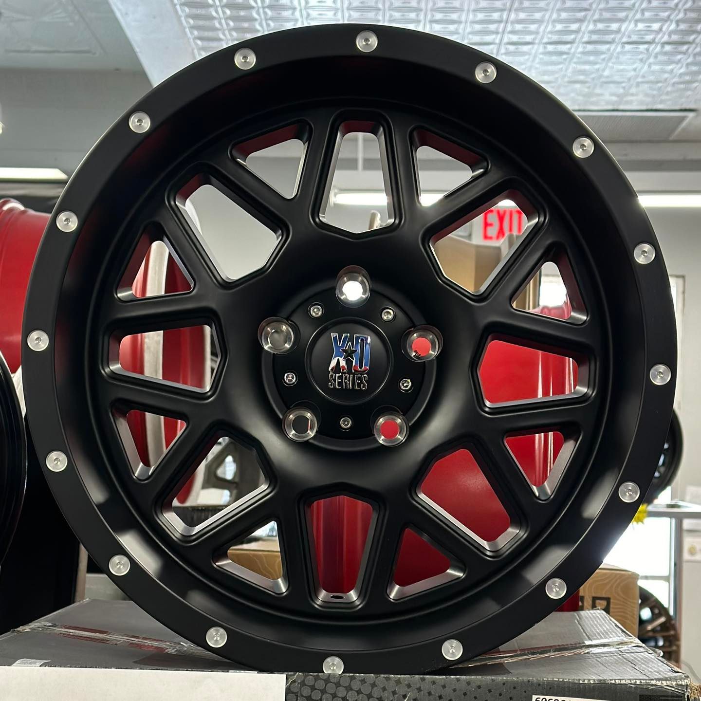 Black off-road wheel rim with silver bolts, displayed indoors on a counter.