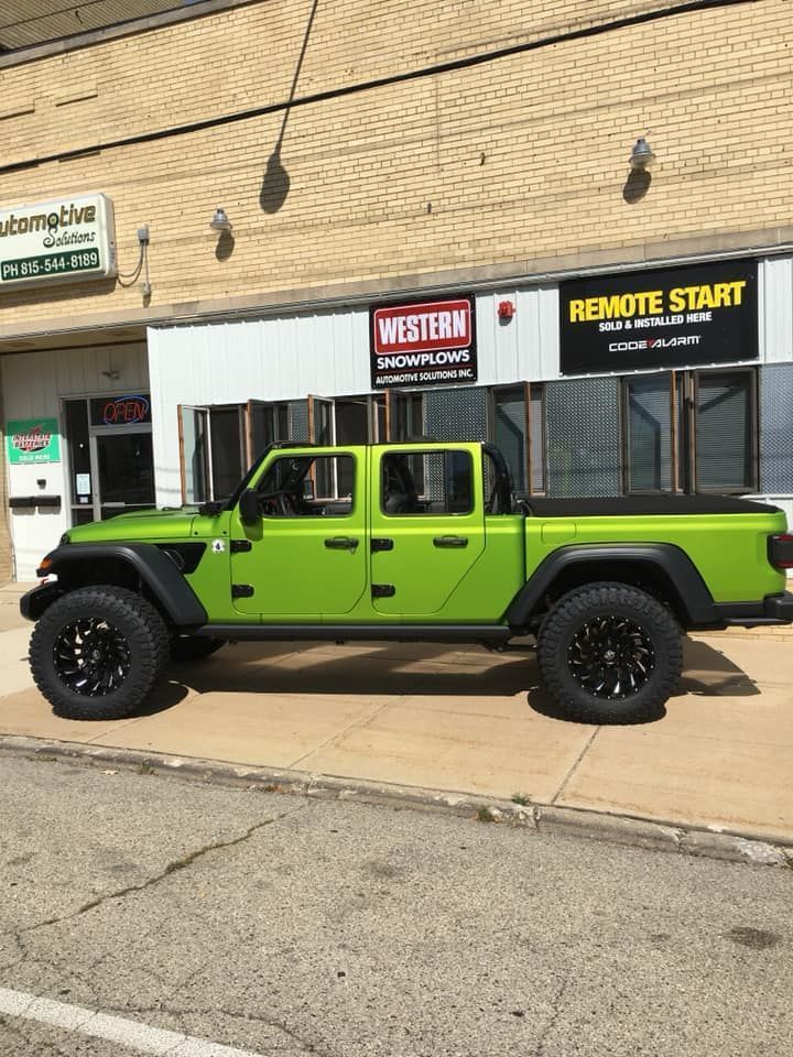 Bright green lifted pickup truck parked outside a storefront with “REMOTE START” signage